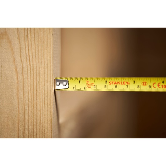 STANLEY 0-30-686 tape measure measuring wood surface, close-up side view.