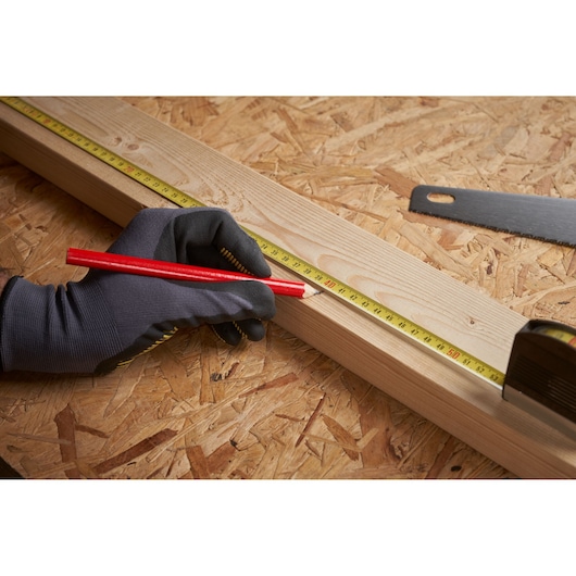 STANLEY 0-32-125 tape measure used to mark wood with red pencil, close-up on workbench.