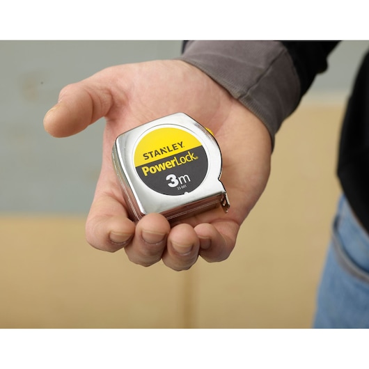 Photo of STANLEY 0-33-041 PowerLock 3m tape measure held in hand, silver case with yellow and black label.