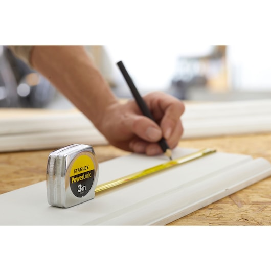 STANLEY 0-33-041 tape measure PowerLock 3m on wood, hand marking measurement with pencil.