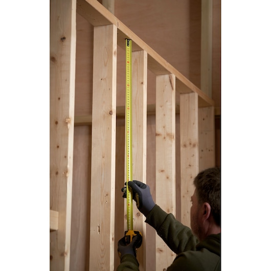 STANLEY 0-33-720 tape measure in use on wooden frame, vertical measurement against timber studs.