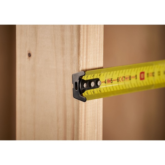 STANLEY 0-33-811 tape measure extended, measuring a wooden beam, close-up photo.