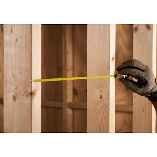 STANLEY 0-39-055 tape measure used to measure distance between wooden studs, close-up view.