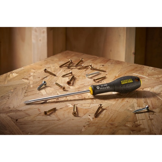 STANLEY 0-65-209 Phillips screwdriver with black and yellow handle on wooden surface with assorted screws.