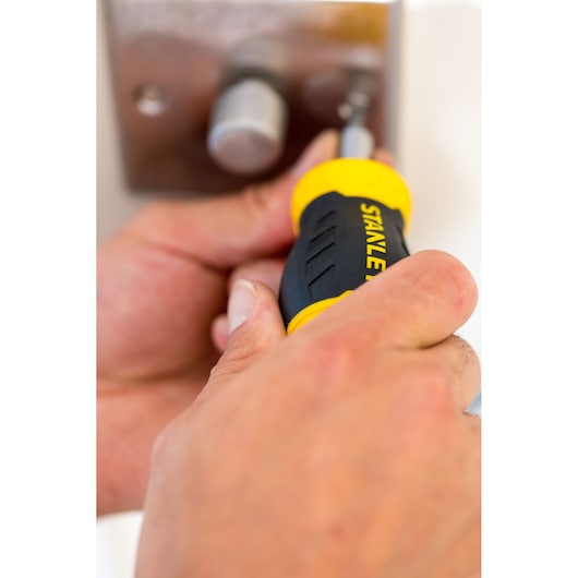 Photo of STANLEY 0-66-357 screwdriver with black and yellow handle being used to tighten a screw on a metal plate.