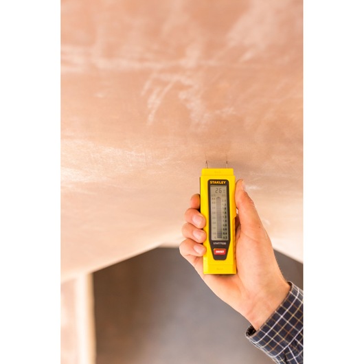 Photo of STANLEY 0-77-030 moisture meter used on plaster wall, held in hand.