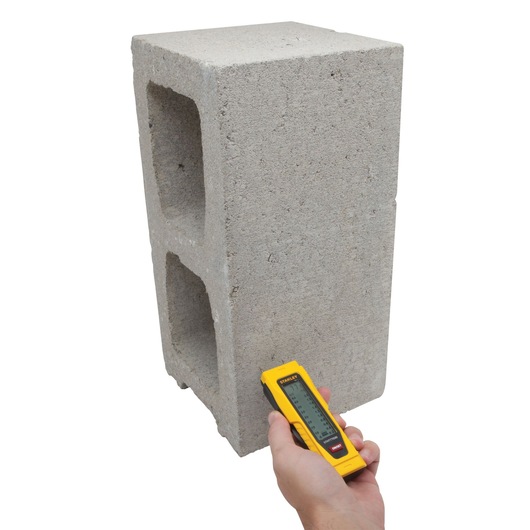 STANLEY 0-77-030 laser distance measurer applied to concrete block, front angle, product demonstration.