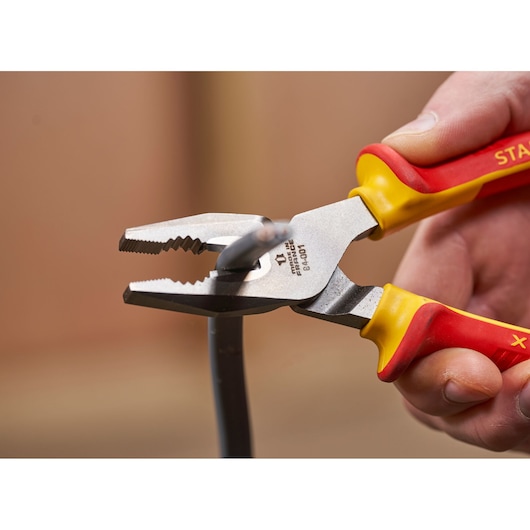 STANLEY 0-84-001 pliers with red and yellow handles cutting wire, close-up photography.