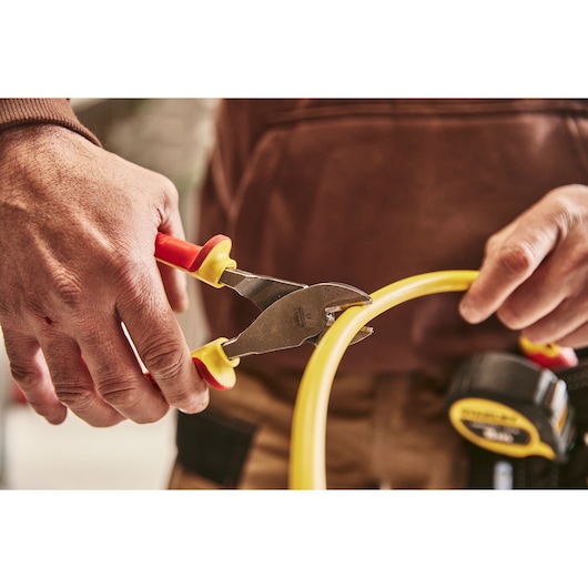 STANLEY 0-84-004 insulated pliers cutting yellow cable in workshop setting.