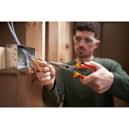Photo of STANLEY 0-84-007 insulated pliers gripping electrical wire near metal junction box during installation.