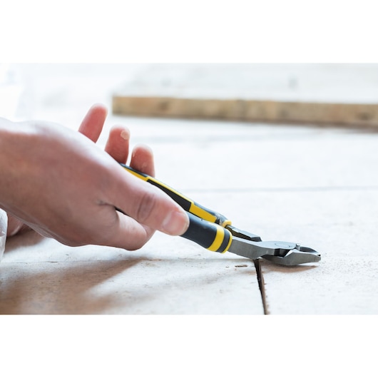 Photo of STANLEY 0-89-860 diagonal cutting pliers with yellow and black grips in use on tile floor.