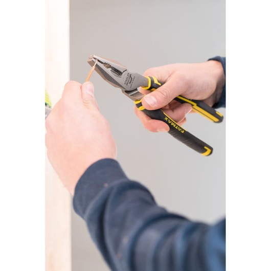 STANLEY 0-89-868 pliers being used to cut wire, close-up of black and yellow tool in hand.