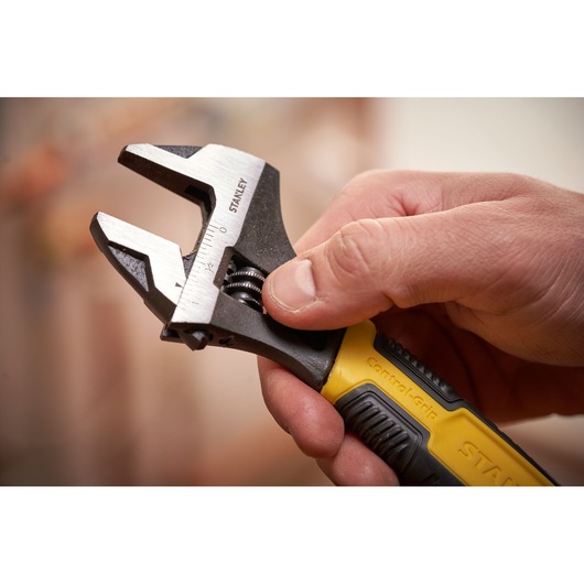 STANLEY 0-90-950 adjustable wrench with yellow and black handle held in hand, close-up.