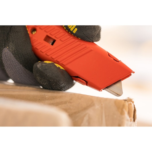 STANLEY 1-10-189 red utility knife close-up cutting cardboard, gloved hand holding tool.