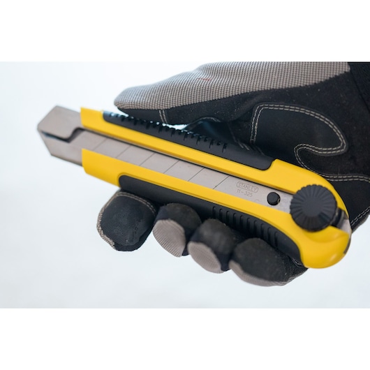 STANLEY 1-10-425 utility knife in yellow and black, side angle, held by a gloved hand.