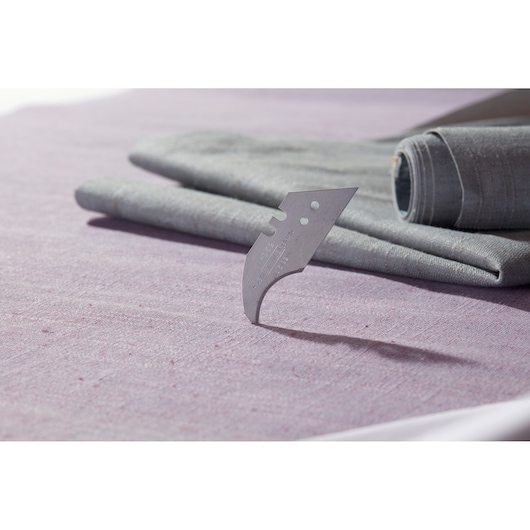 STANLEY 1-11-952 curved carpet blade standing upright on fabric, close-up side angle photography.
