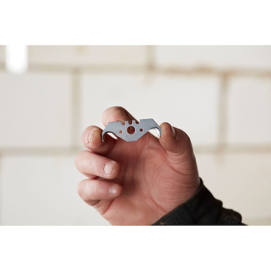 STANLEY 1-11-967 utility blade held in hand, close-up view, silver metal with distinctive cutouts.