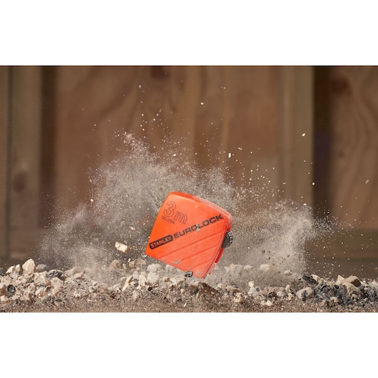 STANLEY 1-30-299 orange EUROLOCK tape measure photography on rocky ground with dust impact.
