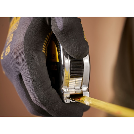 STANLEY 1-33-194 tape measure held in gloved hand, yellow blade extended, close-up photography.