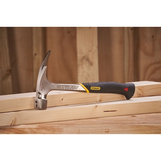 STANLEY 1-51-937 claw hammer with black and yellow handle resting on wooden beams, side angle.