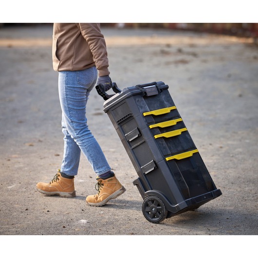 STANLEY 1-79-206 rolling tool chest with yellow drawers, photographed outdoors being pulled by a person.