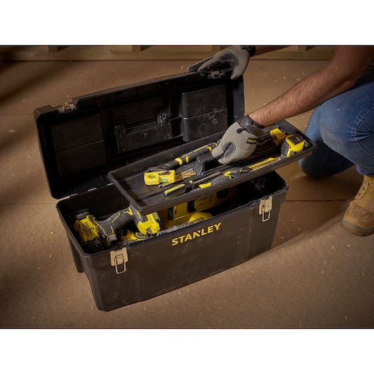 STANLEY 1-94-859 photography of black tool box with yellow tools on workshop floor, lid open, angled view.