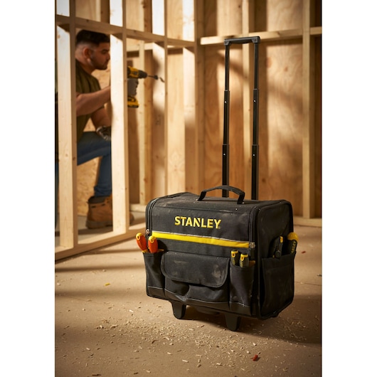 STANLEY 1-97-515 rolling tool bag with telescopic handle on construction site, front angle.