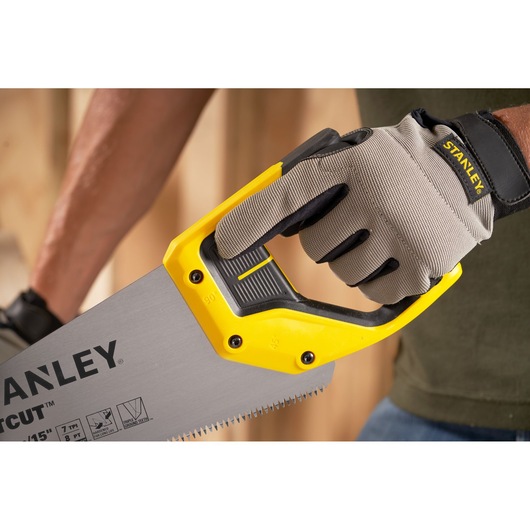STANLEY 2-15-281 hand saw with yellow and black handle held by gloved hand, close-up angle.