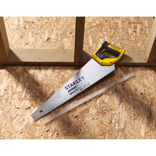 STANLEY 2-15-288 hand saw with yellow and black handle on wood panel, top view.