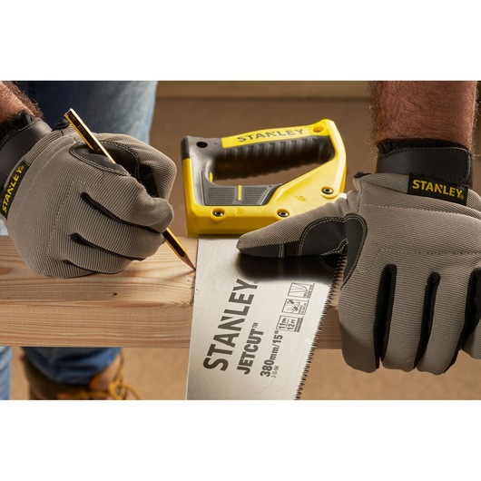 STANLEY 2-15-594 hand saw in use, gloved hands marking wood, pencil and yellow handle visible.