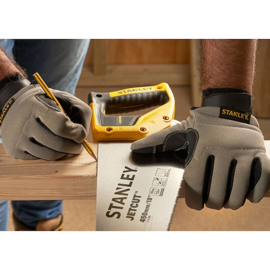 Photo of STANLEY 2-15-595 hand saw and gloves on wood, with a pencil and yellow STANLEY tool in background.