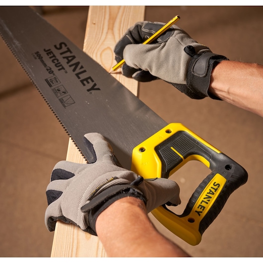 STANLEY 2-15-599 hand saw with yellow and black handle marking wood, close-up angle.