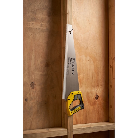 STANLEY 2-15-599 hand saw with yellow handle in side view against wooden boards.