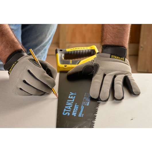 Photo of STANLEY 2-20-149 hand saw used for marking with gloves and pencil on a work surface.
