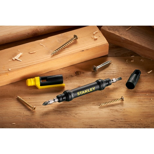 STANLEY 66-344M double-ended screwdriver with black handle, surrounded by screws and wooden planks, angled view.