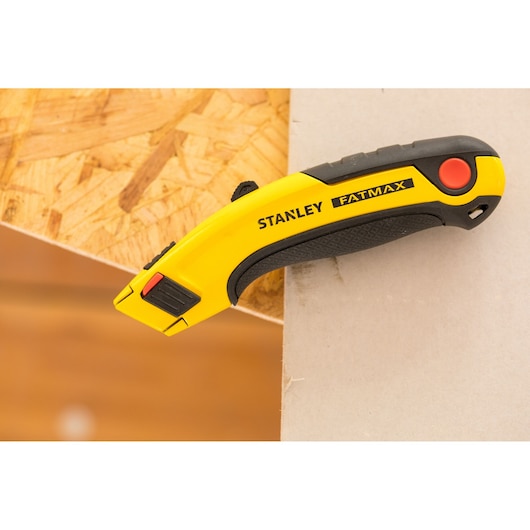 STANLEY 7-10-778 utility knife FATMAX, yellow and black, side angle, on wood and drywall.