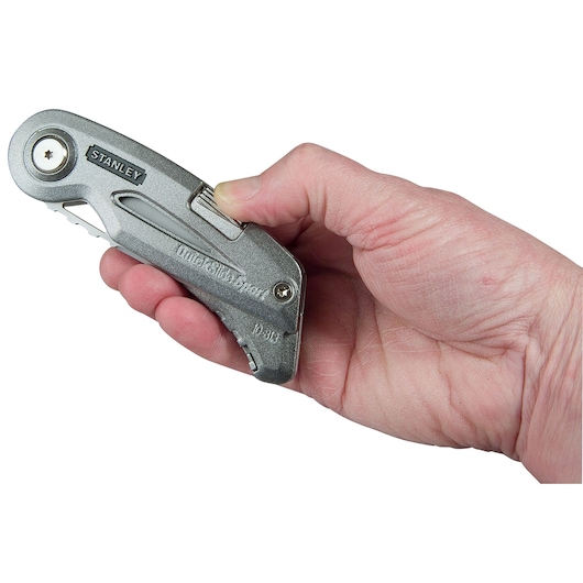 Photo of STANLEY 9-10-813 folding utility knife held in a hand, silver metallic finish, side view.