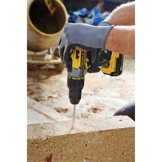 STANLEY FMC625M2S cordless drill being used to drill into concrete, close-up view of tool in use outdoors.