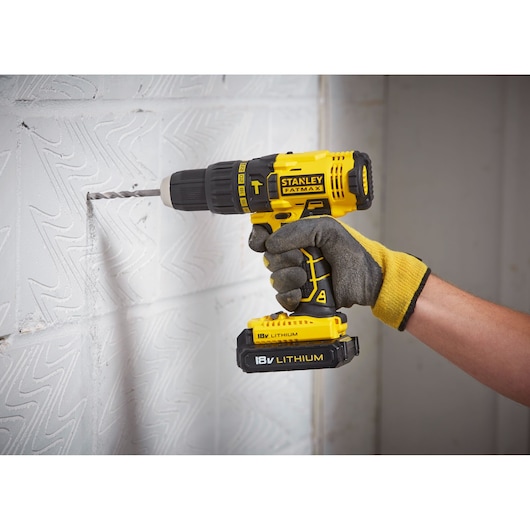 STANLEY FMC626C2K cordless drill with 18V lithium battery drilling into a white patterned wall.
