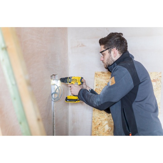 STANLEY FMC626D2K cordless drill in use on wall by person during construction work.