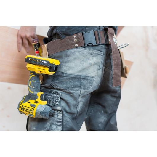 STANLEY FMC647B cordless drill in yellow and black attached to tool belt, close-up side view.