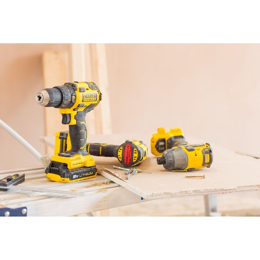 STANLEY FMC647B cordless drill and accessories on workbench, yellow and black finish, side angle.