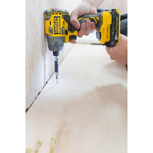 Photo of STANLEY FMC647D2T cordless drill in use on wooden surface, angled side view.