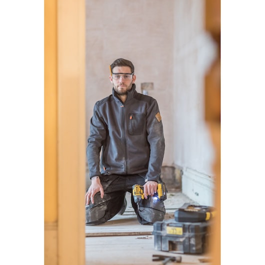 STANLEY FMC647D2T cordless drill in use, worker kneeling, tool case visible, indoor construction setting.