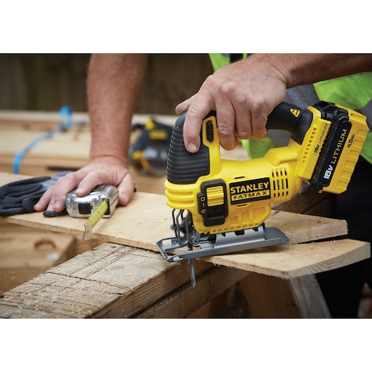 STANLEY FMC650B jigsaw tool in use cutting wood, close-up side angle, yellow and black design.