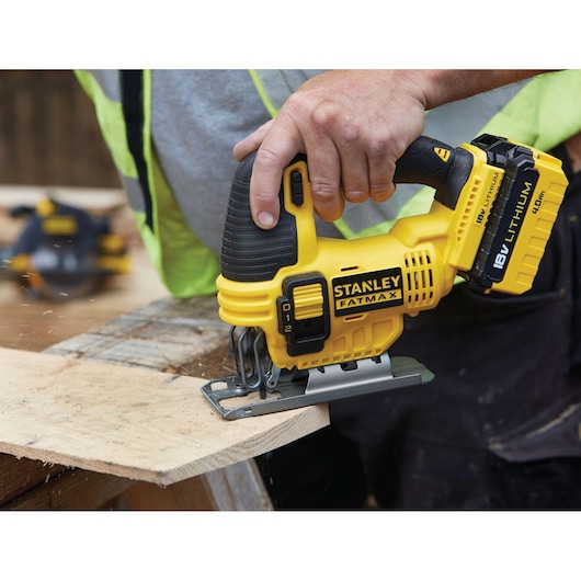 STANLEY FMC650B jigsaw in use, yellow and black design, cutting wood, close-up handheld view.