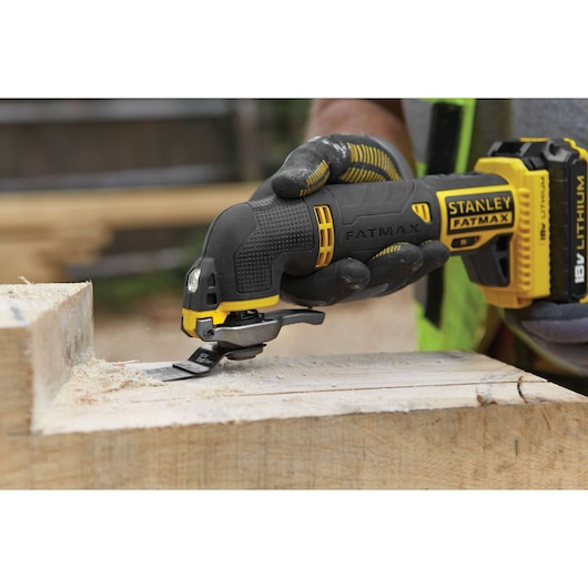 STANLEY FMC710B cordless multi-tool cutting wood, close-up with gloved hand, outdoor workshop.