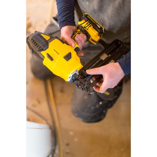 STANLEY FMC792D2 cordless nail gun in use, yellow and black, construction setting.
