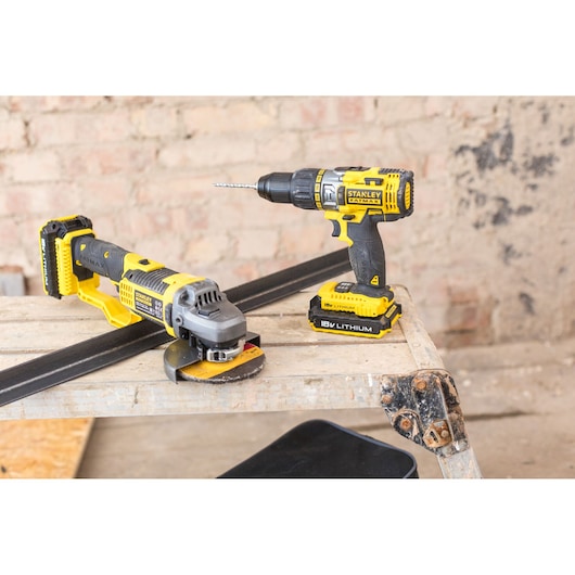 STANLEY FMCK464D2 drill and angle grinder set on a wooden bench in a workshop.