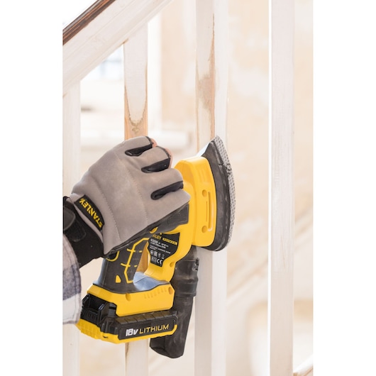 STANLEY FMCW210B cordless sander in use on staircase railing, close-up of yellow and black tool.